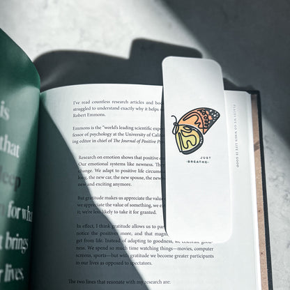 Single line butterfly art bookmark laying on open book page.