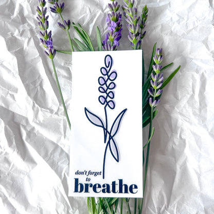 Clear window cling of lavender with words "don't forget to breathe" on lavender flowers on paper background.