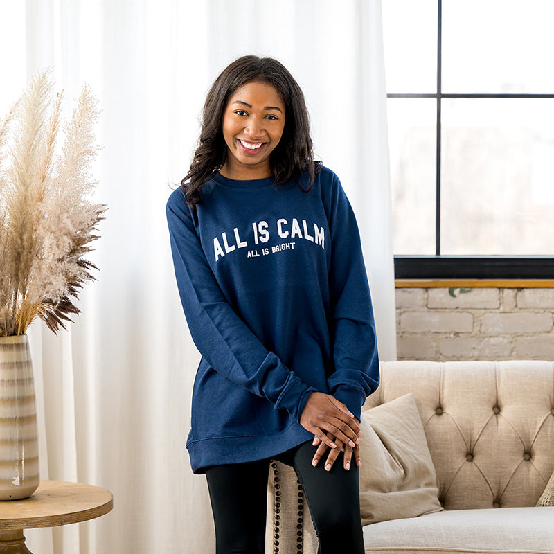 Woman smiling in navy blue All is Calm crewneck sweatshirt.