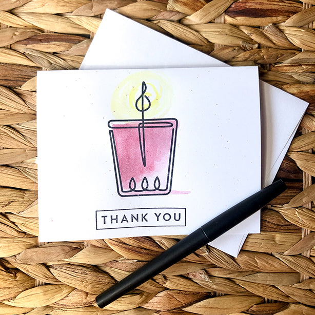 Watercolor and stamped note card of pink candle wrapped in twine on basket pattern with pen.