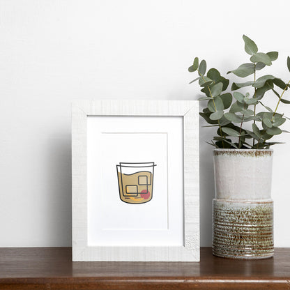 Black single-line art of old fashioned drink on white, framed in wood, displayed near vase of eucalyptus on wooden shelf.