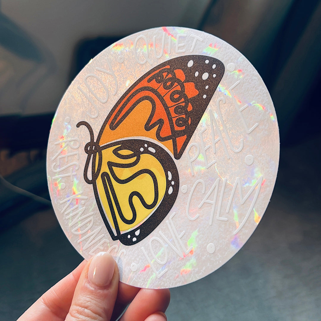 Hand holding rainbow suncatcher sticker with butterfly.